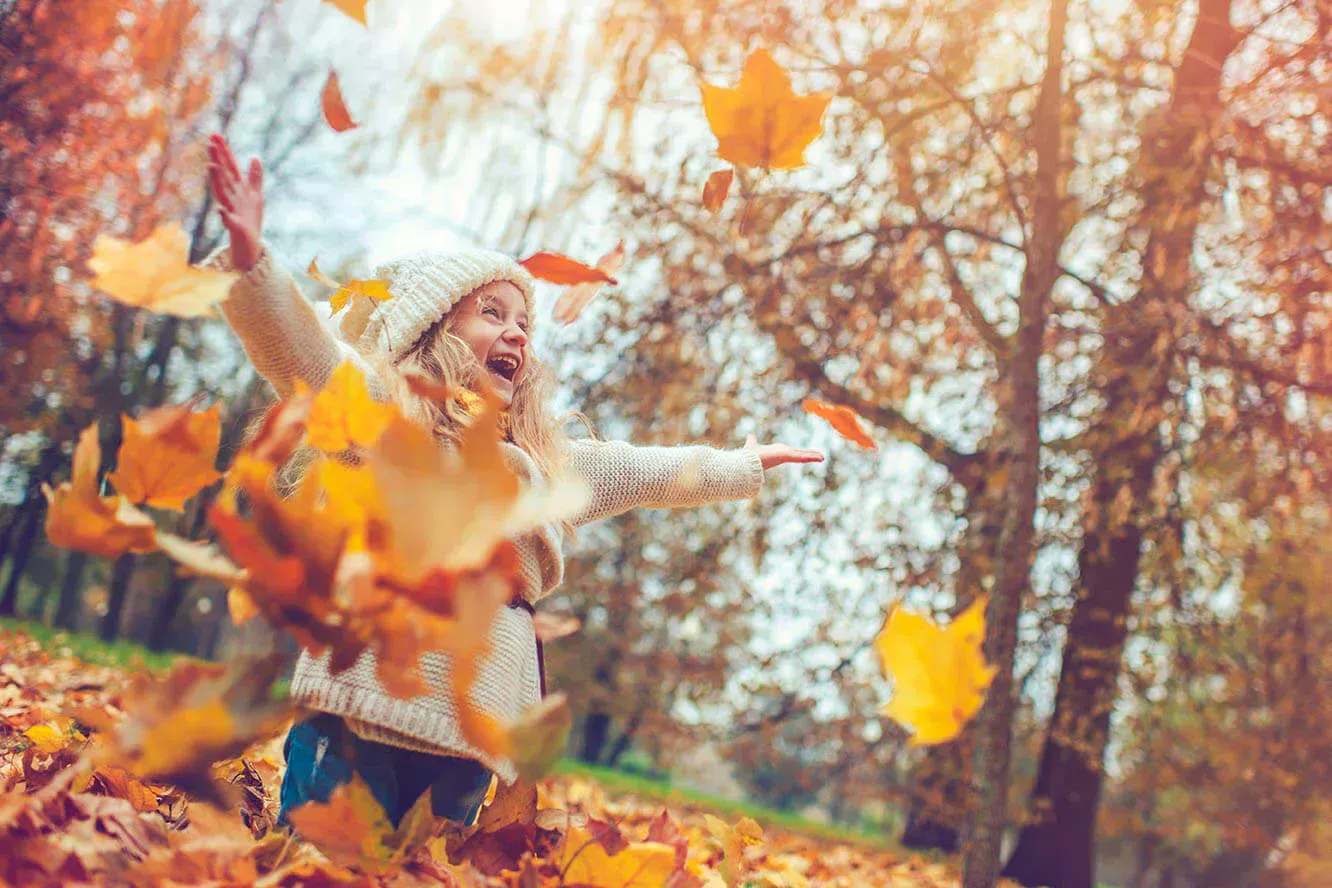 Petite fille qui joue avec les feuilles dans le feuillage